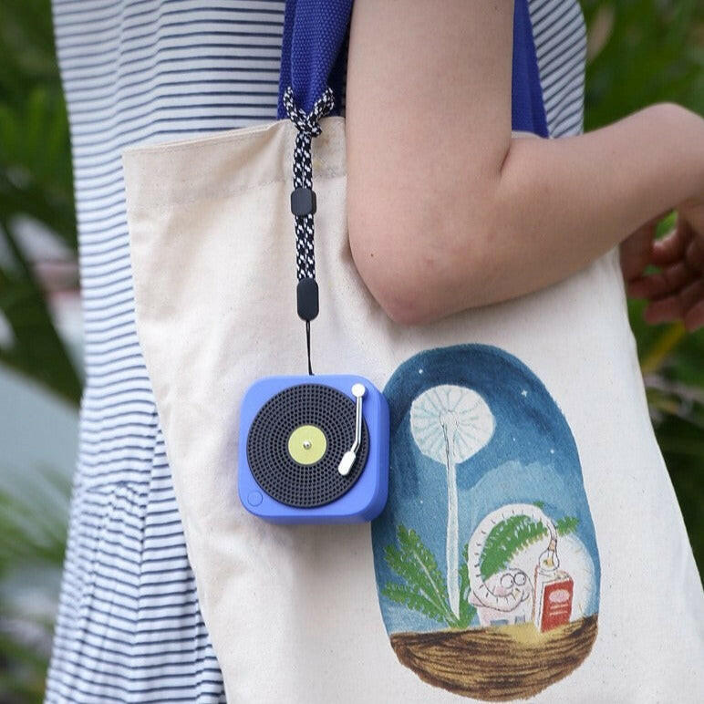 blue portable bluetooth speaker carried on a girl's bag